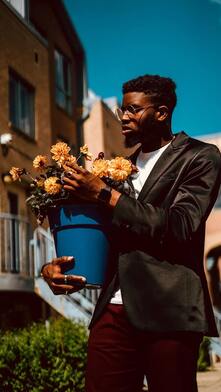 Man wearing a blazer holding a potted flower
