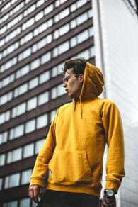 Man in a yellow hoodie with a building behind