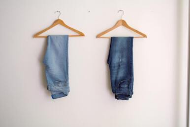 Two pairs of blue jeans on hangers